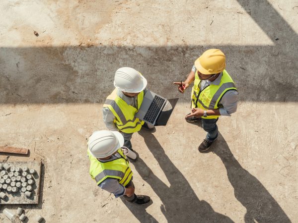 Top view, Team engineer building inspection use computer laptop and blueprint working at construction site. Teamwork discussing at workplace.